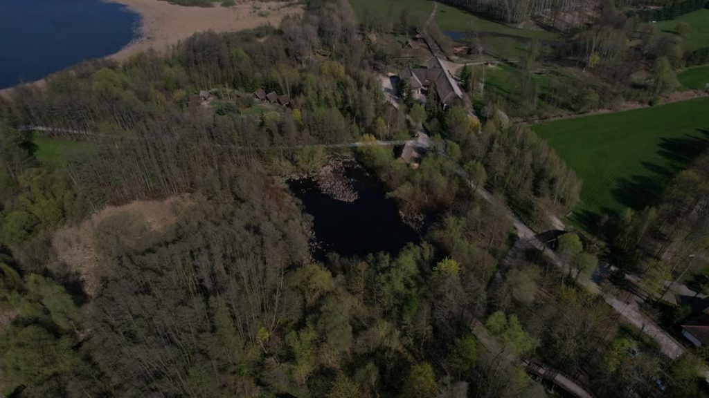 A breathtaking aerial view capturing forests, roads, and a scenic village beside a tranquil lake.